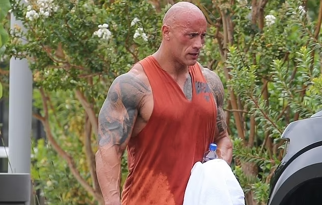 Dwayne Johnson flexes bulging biceps in an orange sweat-soaked tank top after grueling work out in Los Angeles