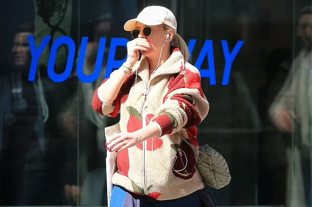 Scarlett Johansson tries her best to blend into the NYC crowd in a hat and sunglasses with an apple print jacket as she carries two bags