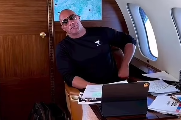 Dwayne Johnson showcases his muscular arms as he tries to use 'the force' to get work done on his private jet