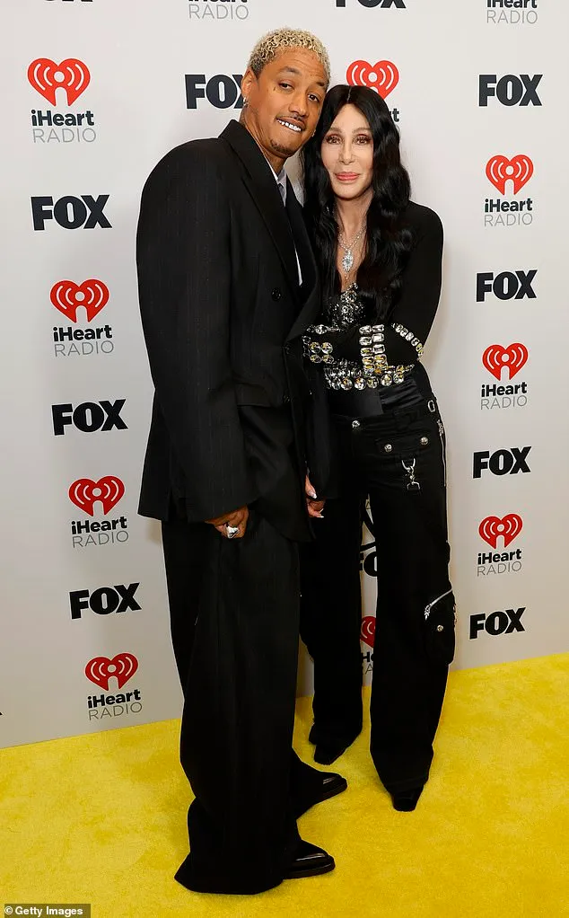 Cher, 77, gets a kiss from lover Alexander Edwards, 38, as he supports her at the 2024 iHeartRadio Music Awards Cher, 77, gets a kiss from lover Alexander Edwards, 38, as he supports her at the 2024 iHeartRadio Music Awards