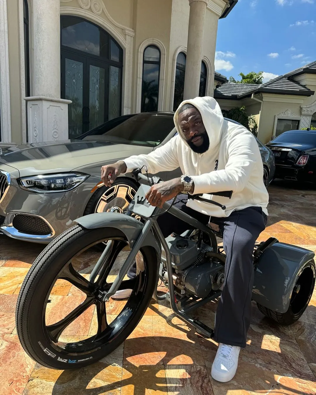 Rick Ross Flexes in Style on a Custom Trike, Surrounded by Luxury Cars at His Lavish Mansion!