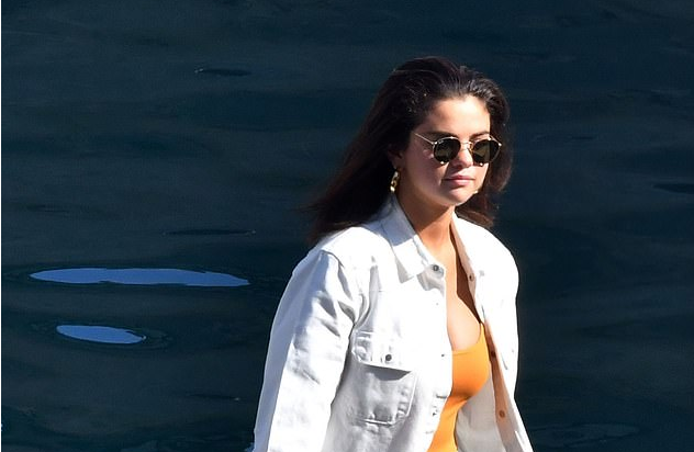 Selena Gomez embraces an off-duty look in white denim jacket and cut-off shorts as she enjoys a boat trip along Amalfi Coast