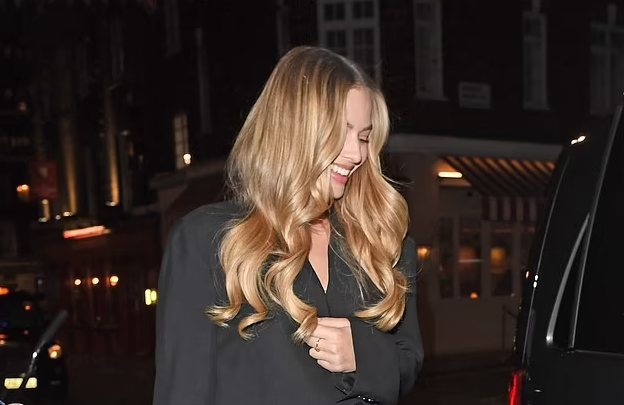 Margot Robbie spices up her tasteful black overcoat with Barbie pink shoes and clutch as she dines with her husband and friends in London