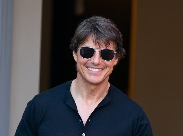 Tom Cruise flashes a huge smile and a friendly wave as he arrives in London by helicopter